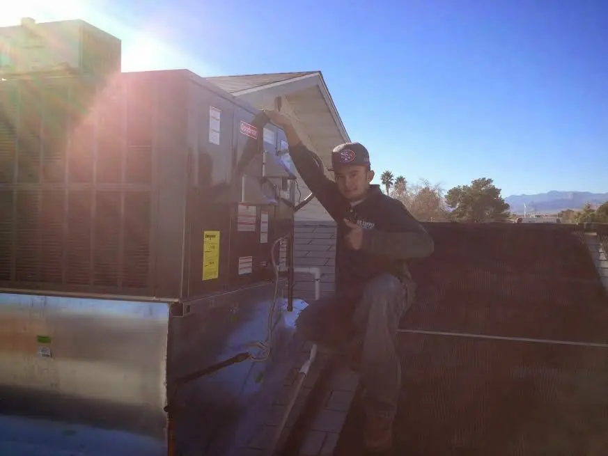 HVAC technician performing Air Duct Repair on a rooftop unit in Peoria